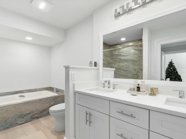 full bathroom with hardwood / wood-style flooring, toilet, vanity, and shower with separate bathtub