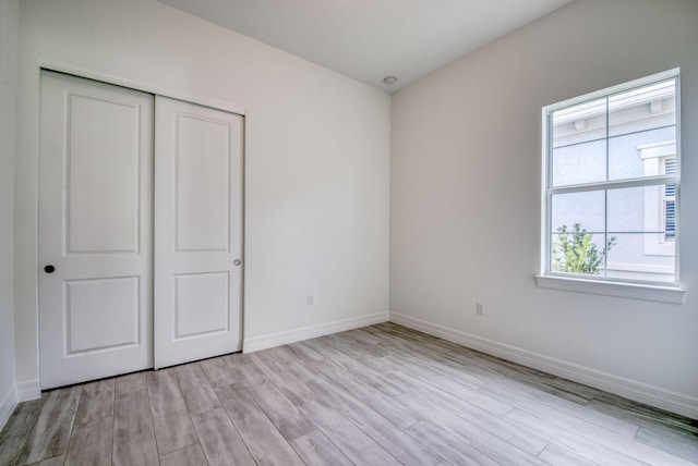 unfurnished bedroom featuring light hardwood / wood-style flooring and a closet