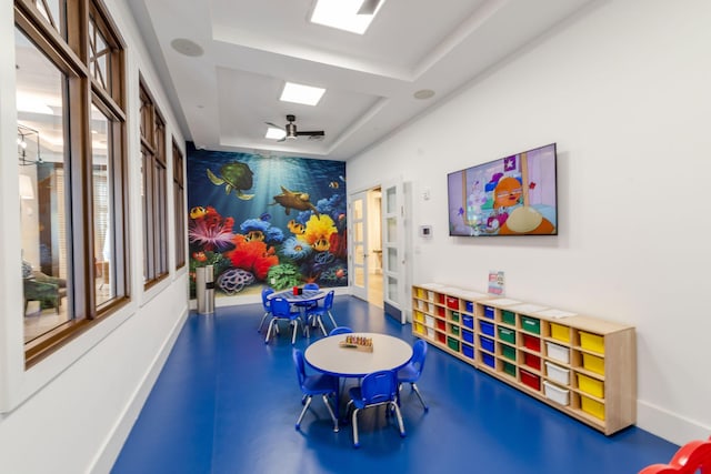 recreation room with a tray ceiling and ceiling fan