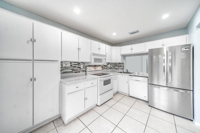 kitchen featuring white appliances, white cabinets, sink, light tile patterned floors, and tasteful backsplash