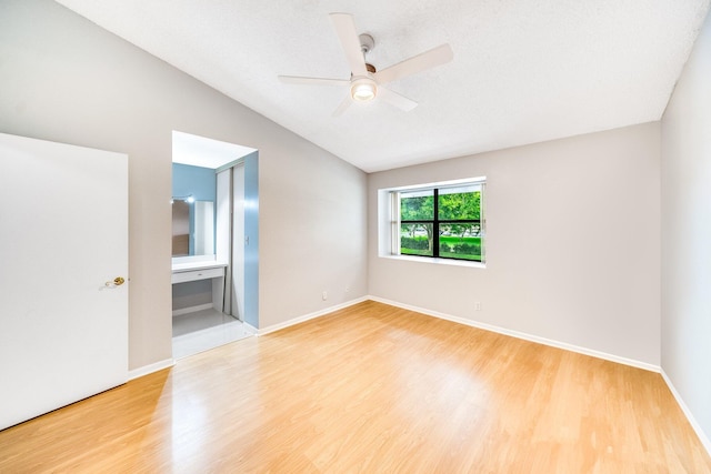 spare room with hardwood / wood-style flooring, vaulted ceiling, and ceiling fan