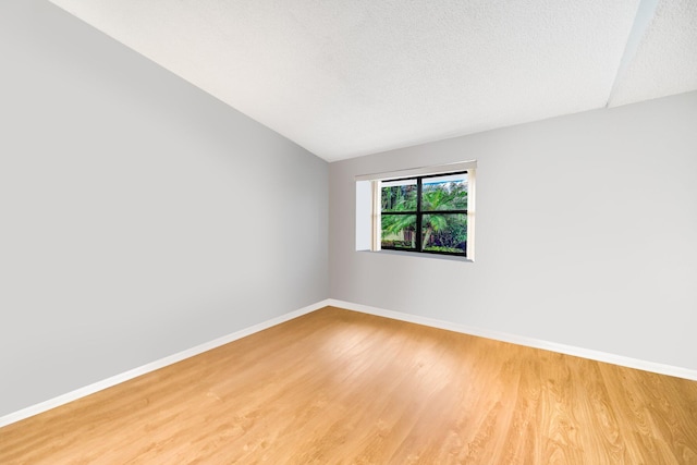 unfurnished room featuring wood-type flooring, lofted ceiling, and a textured ceiling