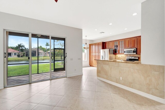 kitchen with sink, appliances with stainless steel finishes, kitchen peninsula, light stone countertops, and backsplash