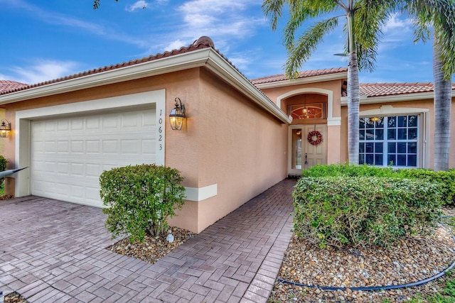10623 Silverton Ln, Boynton Beach, FL 33437 - doorway to property with an attached garage, stucco siding, and decorative driveway