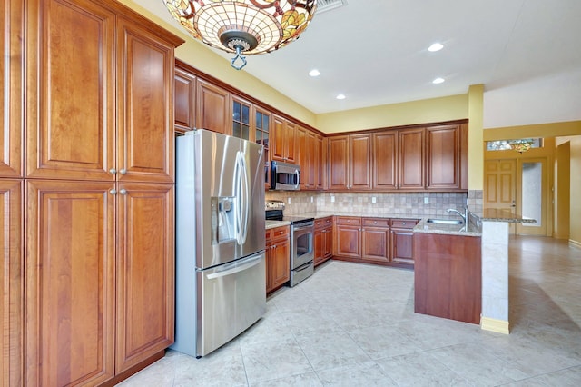 kitchen with sink, appliances with stainless steel finishes, tasteful backsplash, light stone countertops, and kitchen peninsula