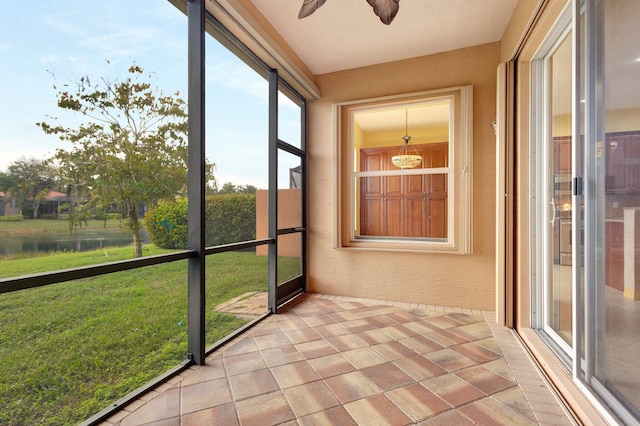 unfurnished sunroom featuring ceiling fan and a water view