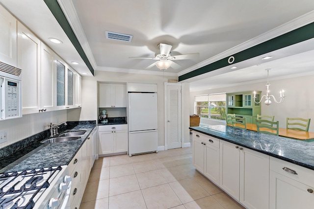 kitchen with white cabinetry, white appliances, ornamental molding, and dark stone counters