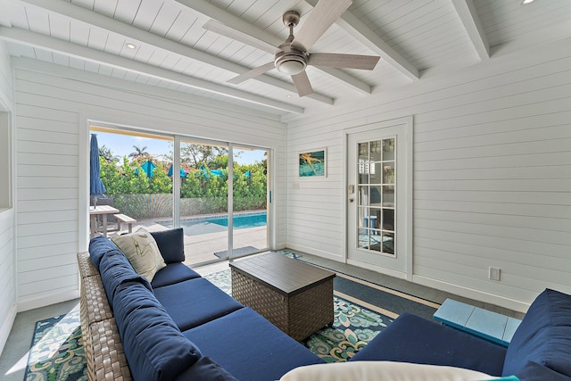 living room featuring beamed ceiling, ceiling fan, and wooden walls