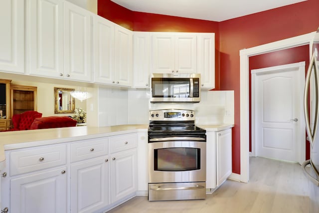 kitchen featuring stainless steel appliances, light wood-type flooring, backsplash, and white cabinetry