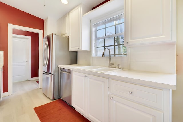 kitchen with sink, white cabinetry, tasteful backsplash, light hardwood / wood-style flooring, and stainless steel dishwasher