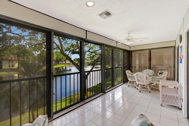 sunroom / solarium with a wealth of natural light, ceiling fan, and a water view