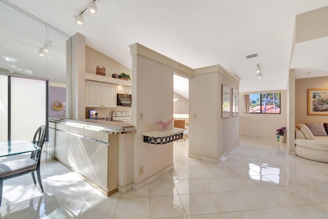 kitchen with light tile patterned flooring, lofted ceiling, and sink