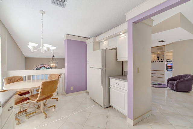 kitchen with white cabinetry, hanging light fixtures, light tile patterned flooring, a chandelier, and white fridge