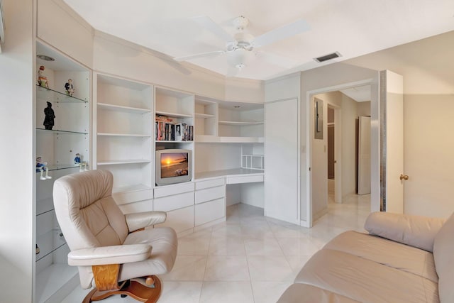 living area with built in desk, ceiling fan, and light tile patterned floors