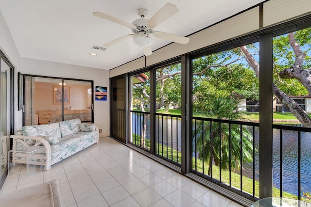 sunroom with ceiling fan and a water view