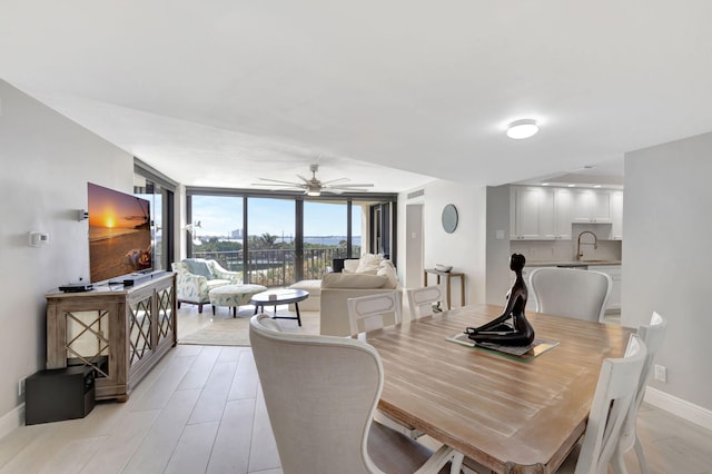 dining area featuring floor to ceiling windows, ceiling fan, sink, and light hardwood / wood-style floors