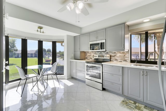 kitchen featuring appliances with stainless steel finishes, backsplash, ceiling fan, sink, and gray cabinets