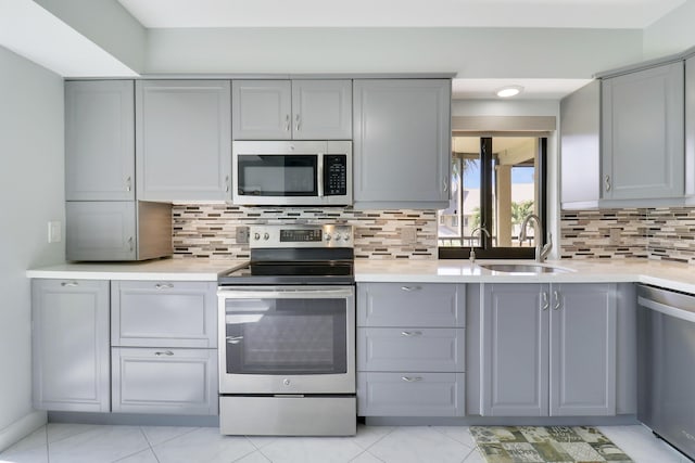 kitchen with tasteful backsplash, gray cabinetry, sink, and stainless steel appliances