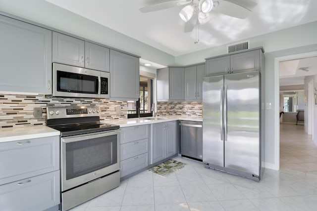 kitchen with tasteful backsplash, gray cabinets, sink, and appliances with stainless steel finishes