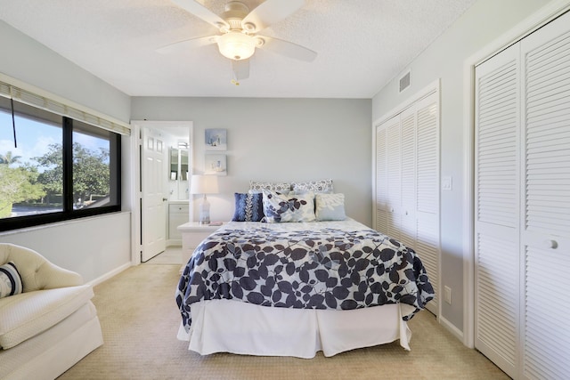 bedroom with multiple closets, ceiling fan, ensuite bath, and light colored carpet