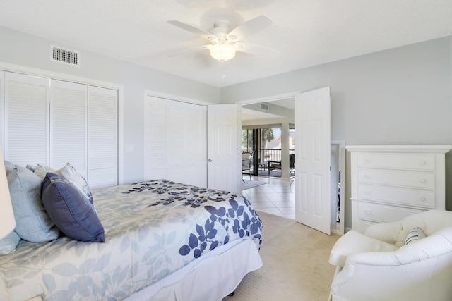 bedroom featuring multiple closets, ceiling fan, and light carpet