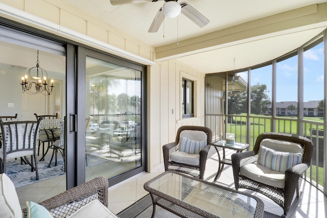 sunroom featuring ceiling fan with notable chandelier