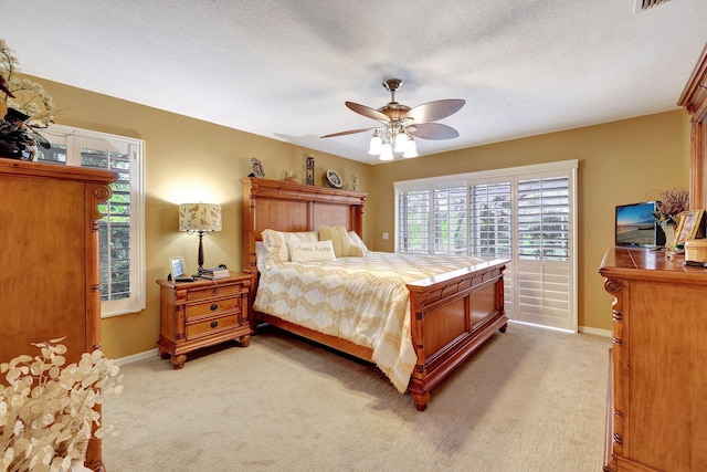 bedroom with a ceiling fan, light colored carpet, a textured ceiling, and baseboards