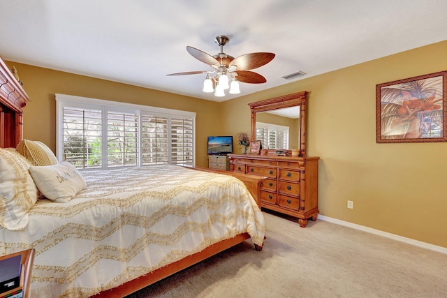 bedroom with light carpet, a ceiling fan, visible vents, and baseboards