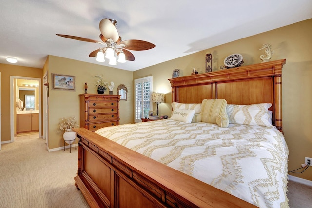 bedroom with ceiling fan, baseboards, ensuite bathroom, and light colored carpet