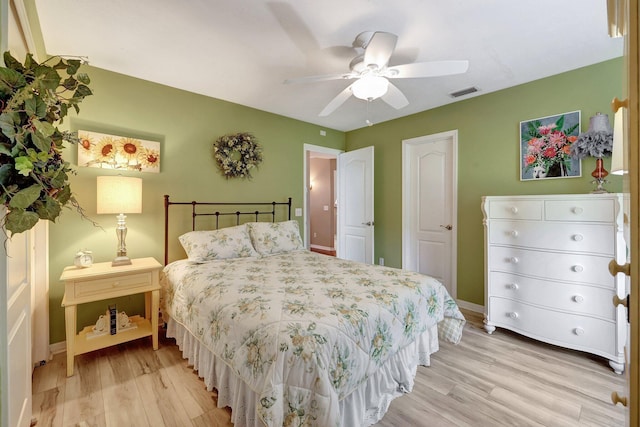 bedroom with a ceiling fan, light wood-type flooring, visible vents, and baseboards