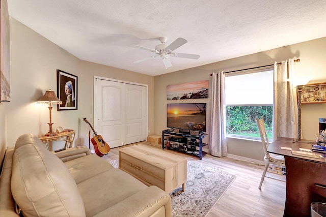 living room featuring a textured ceiling, a ceiling fan, and wood finished floors