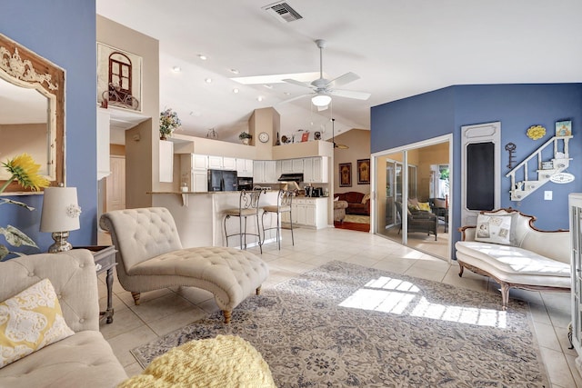 living room with light tile patterned floors, lofted ceiling, visible vents, stairway, and ceiling fan