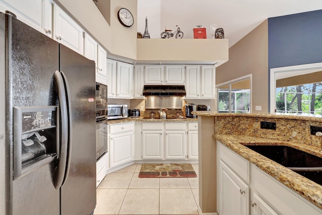 kitchen with light tile patterned floors, white cabinets, light stone countertops, under cabinet range hood, and black appliances