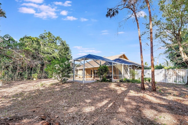 rear view of property with glass enclosure and fence