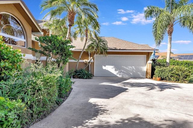 view of front facade with a garage, concrete driveway, and stucco siding