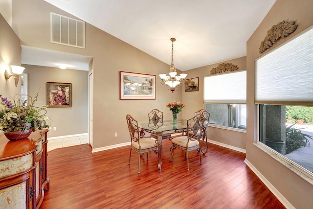 dining room featuring lofted ceiling, visible vents, baseboards, light wood finished floors, and an inviting chandelier