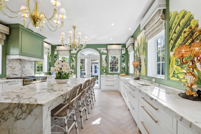 kitchen featuring white cabinetry, light stone counters, a breakfast bar, and light parquet flooring