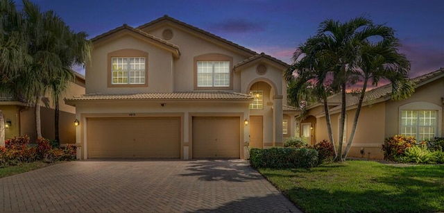 mediterranean / spanish house with a garage and a lawn