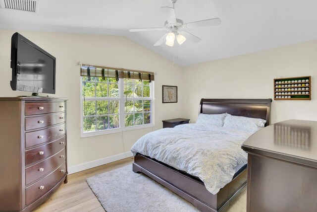 bedroom with ceiling fan, light hardwood / wood-style floors, and vaulted ceiling