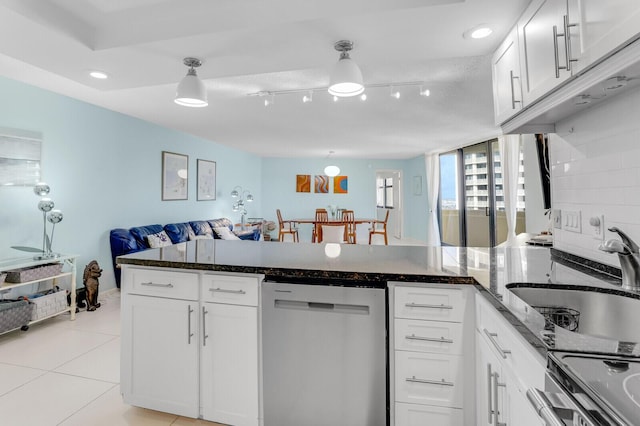 kitchen with kitchen peninsula, appliances with stainless steel finishes, dark stone counters, sink, and white cabinetry