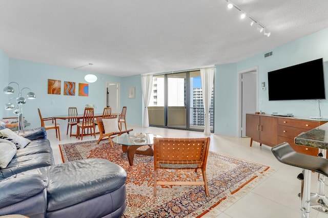 living room with light tile patterned floors, a textured ceiling, and track lighting