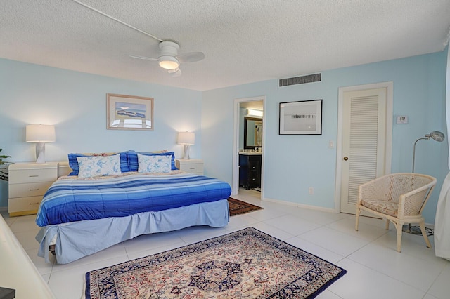 tiled bedroom with a textured ceiling, a closet, ensuite bath, and ceiling fan