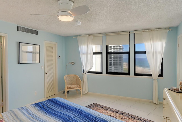 unfurnished bedroom with ceiling fan, light tile patterned floors, a textured ceiling, and a closet