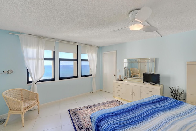 tiled bedroom with ceiling fan and a textured ceiling