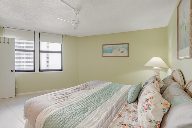 bedroom featuring ceiling fan, light tile patterned floors, and a textured ceiling