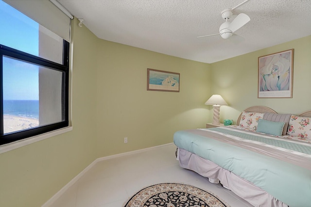 bedroom featuring a textured ceiling, a water view, and ceiling fan