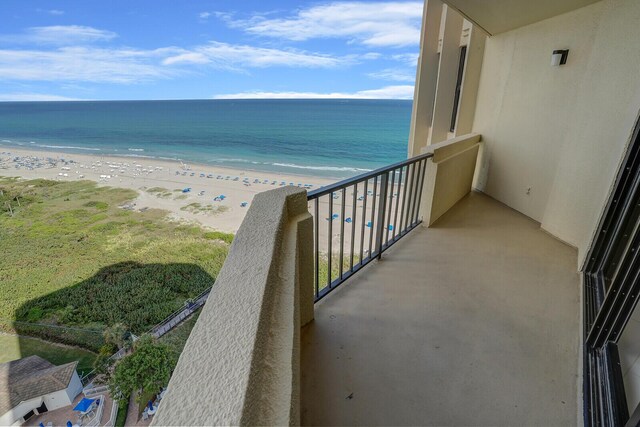 balcony with a water view and a view of the beach