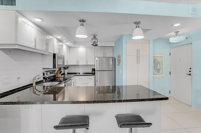 kitchen featuring white cabinetry, hanging light fixtures, and appliances with stainless steel finishes