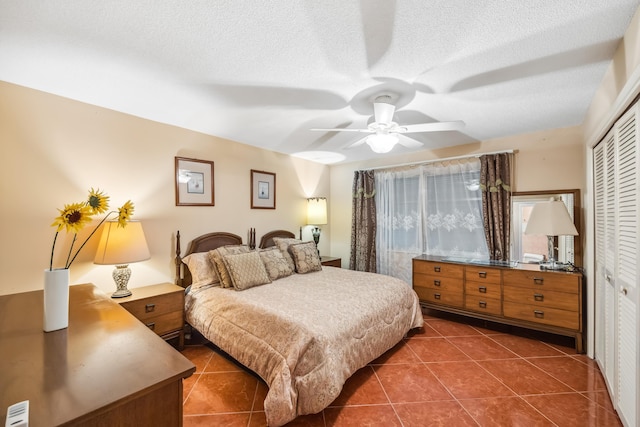 tiled bedroom with ceiling fan, a closet, and a textured ceiling