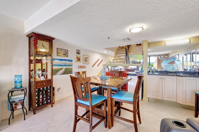 tiled dining room featuring sink and a textured ceiling